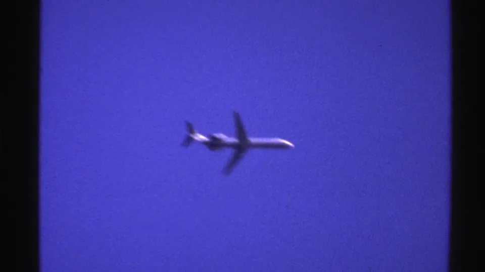 The final 1976 Norway 8mm frame shows the jetliner slightly blurred in motion against blue sky with a dark film edge nearby.