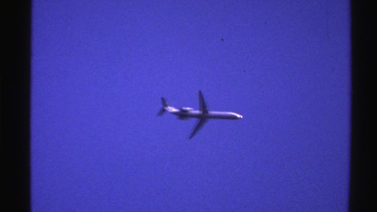 White jet aircraft crossing a deep blue sky.