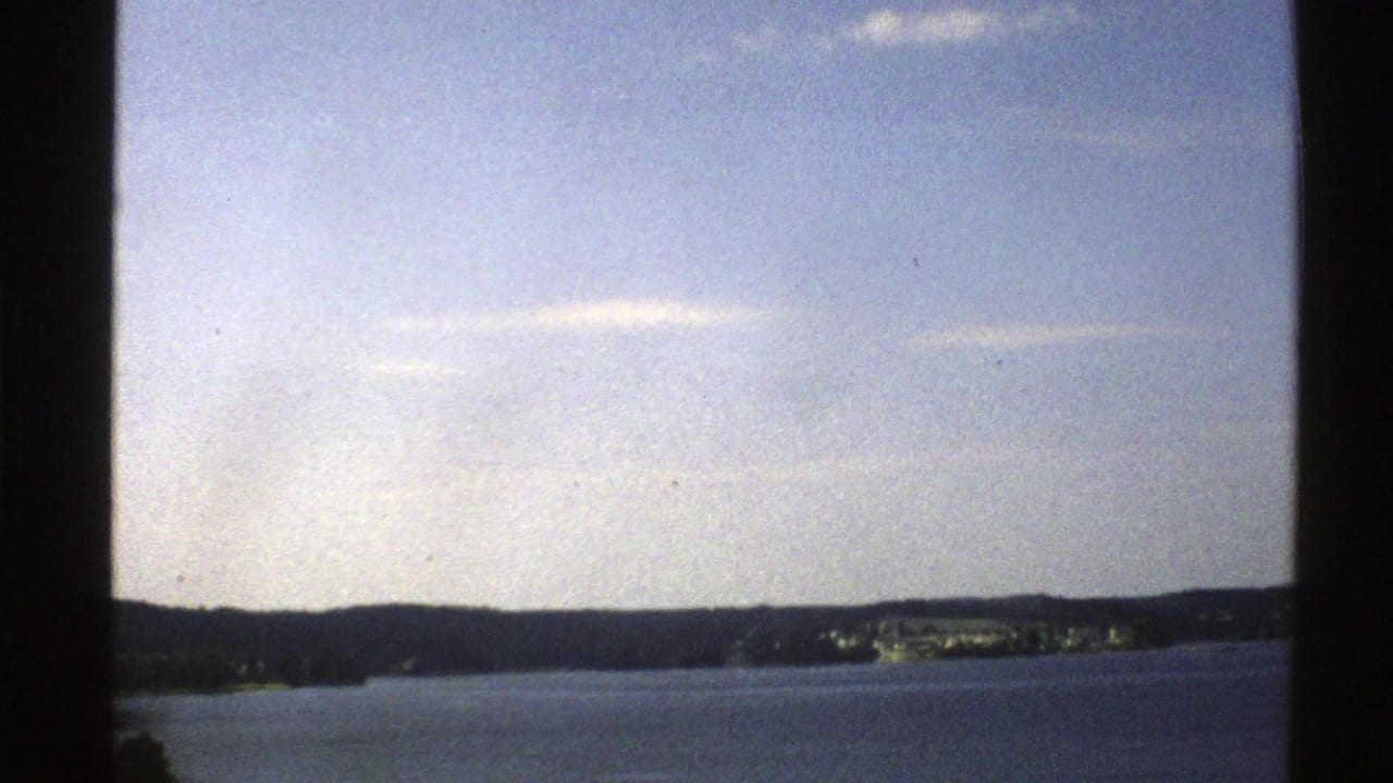 Wide blue water under a pale sky with distant dark mountains and shoreline.