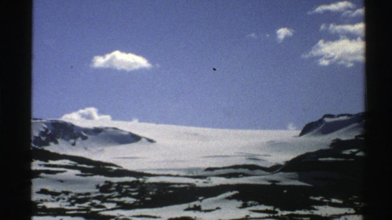 Snow-covered mountain ridge beneath a blue sky with small white clouds and black film borders.