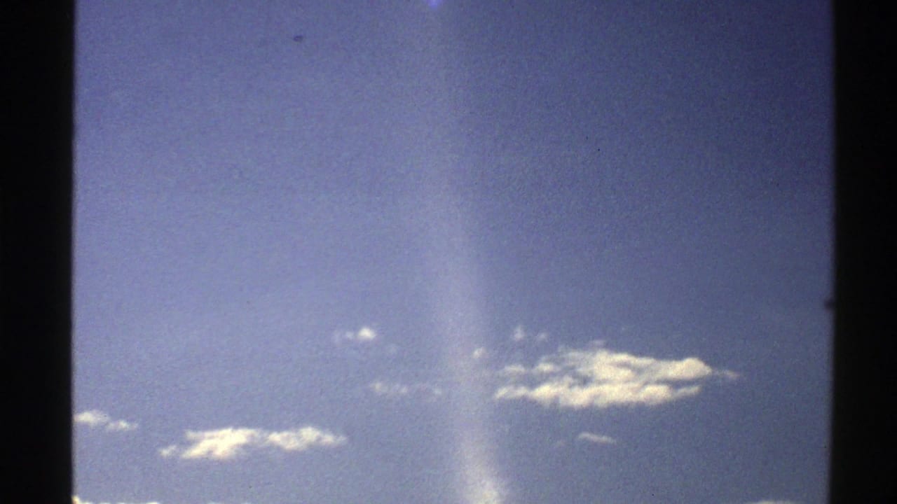 Blue sky with small clouds and dark film-frame borders.
