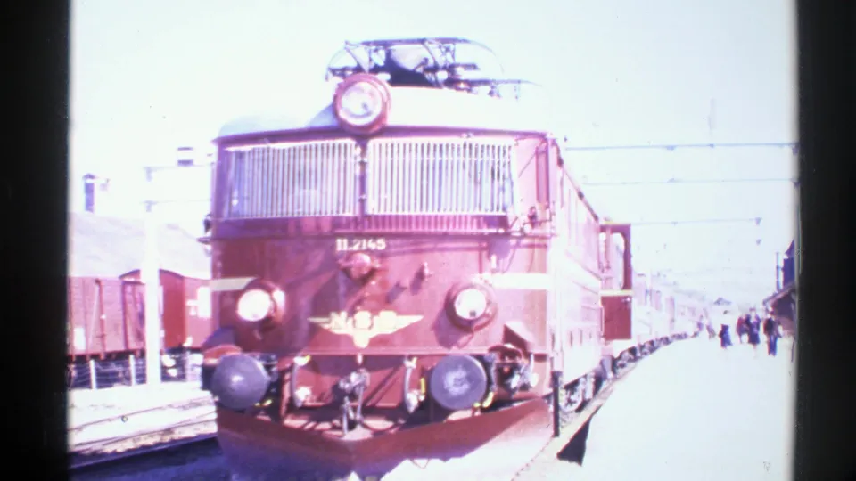 1976 Norway 8mm frame showing red NSB electric locomotive number 11.2145 at a station platform with passengers nearby.