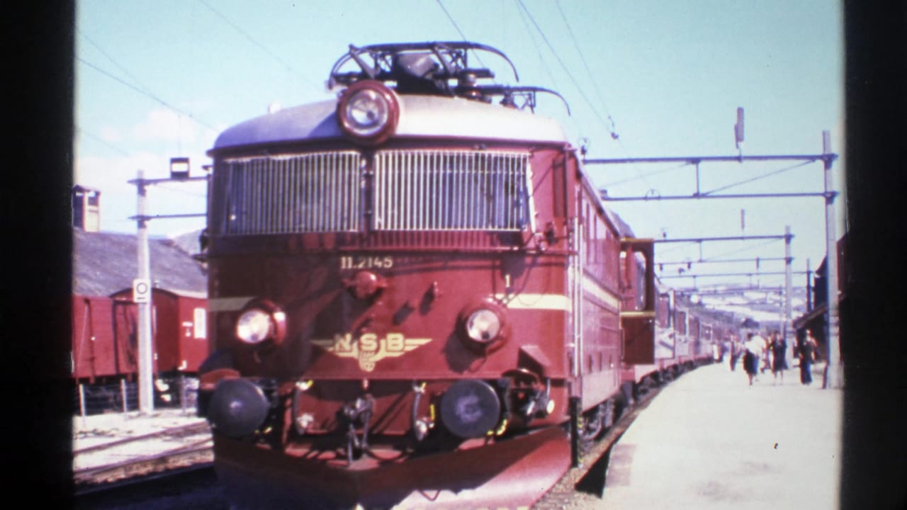 1976 Norway 8mm frame showing a red NSB electric locomotive facing the camera at a platform with railcars and passengers behind it.