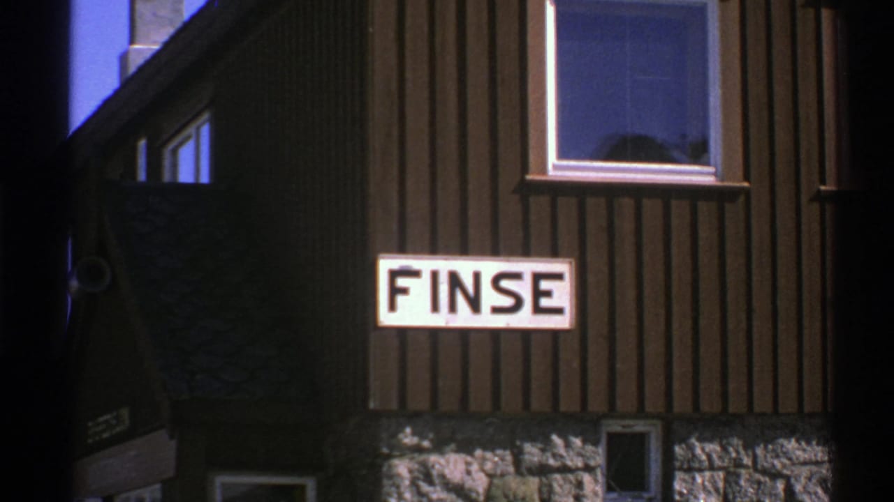 1976 Norway 8mm frame showing a FINSE sign on dark vertical wood siding with windows and a stone base.