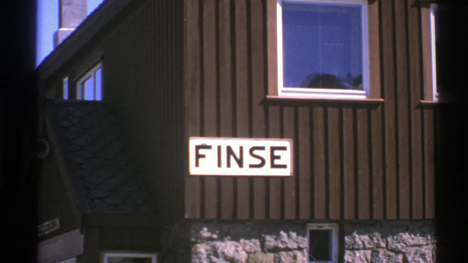 1976 Norway travel frame with the FINSE sign on a dark wooden building and a bright window above it.