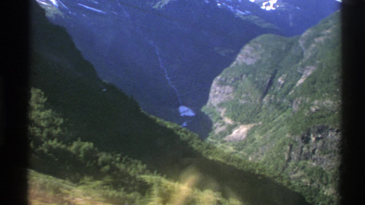 Green fjord mountains viewed through a central dark window divider.