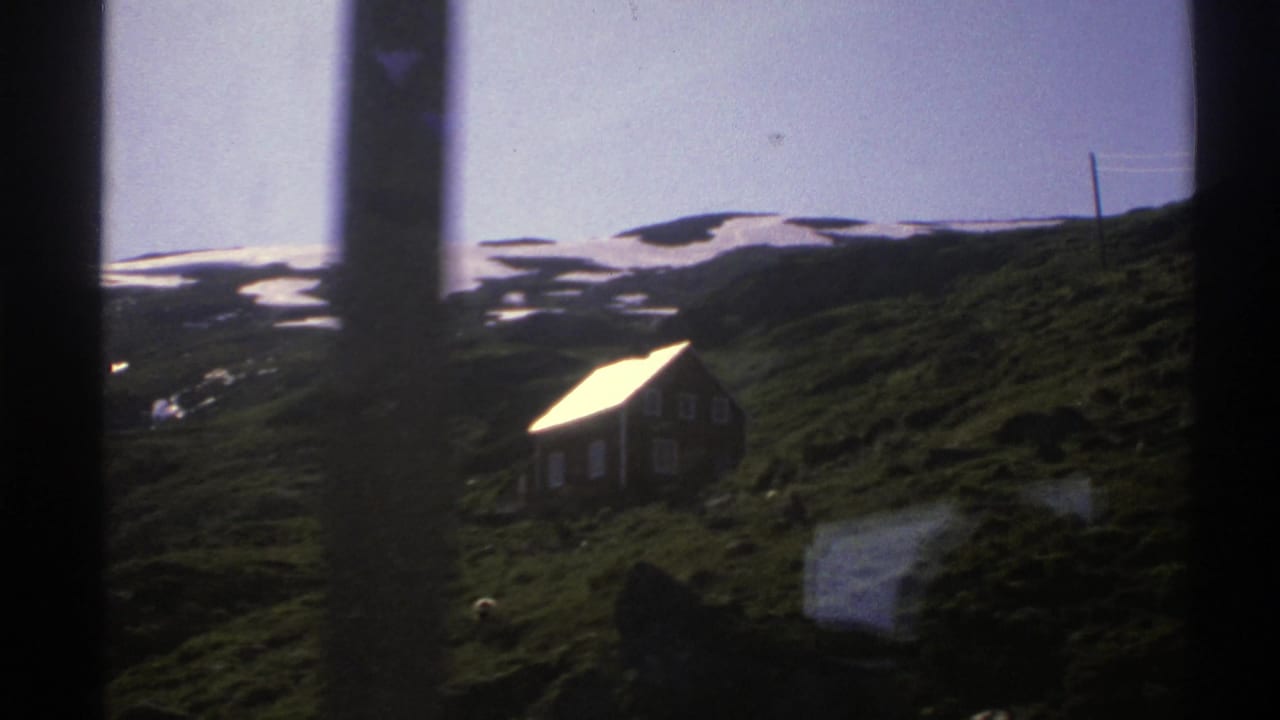 Cottage on a hillside seen through dark vertical frame edges.