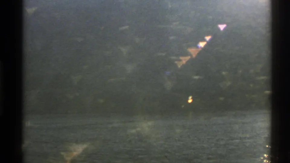 Norwegian lakeside landscape in a soft 8mm frame, with dark vertical edge and triangular light reflections over trees and water.