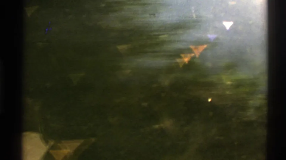 Soft 8mm Norwegian landscape frame with dark water, shoreline trees, bright glare, and reflected triangular light shapes.