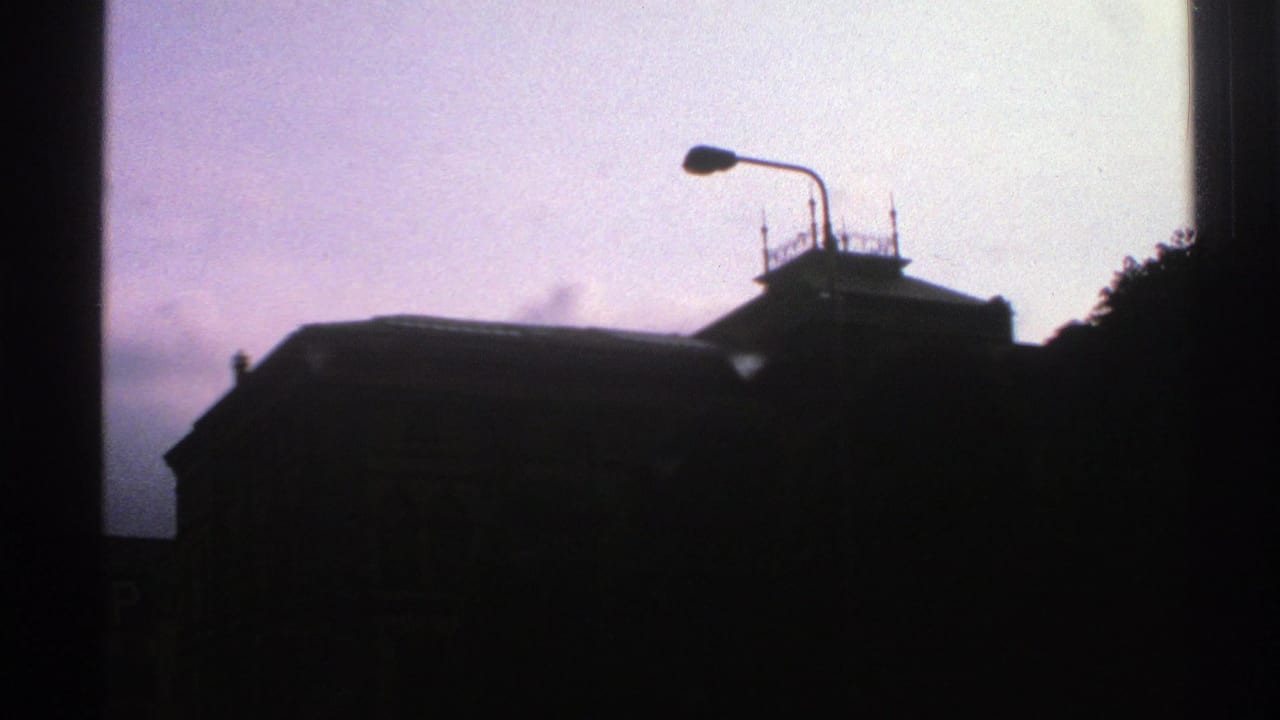 1976 Norway 8mm frame showing a silhouetted building and foreground streetlamp against a purple twilight sky.
