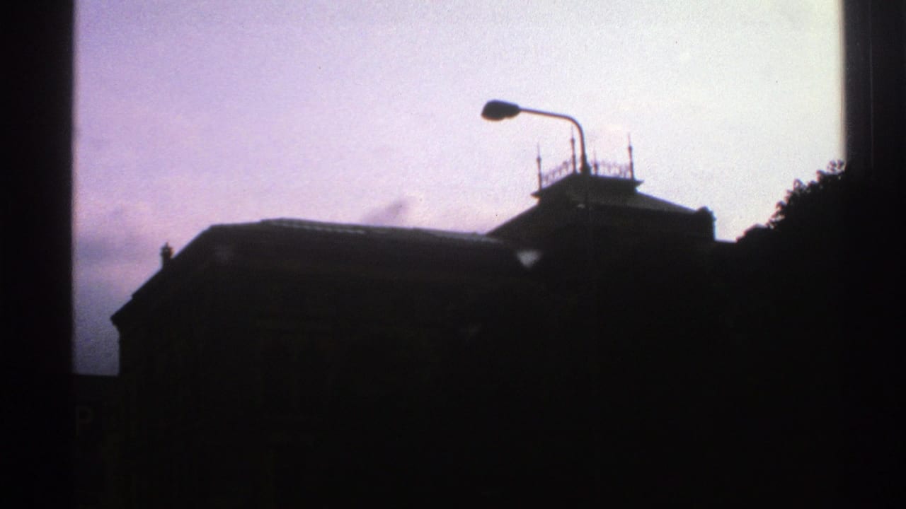 1976 Norway 8mm frame with the building still mostly in shadow, a streetlamp crossing the pale purple sky.