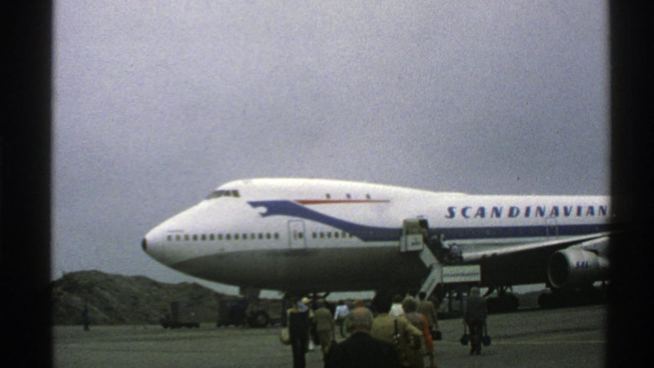 Norway 1976 frame of a Scandinavian Airlines Boeing 747 parked on the tarmac as passengers gather near mobile boarding stairs.
