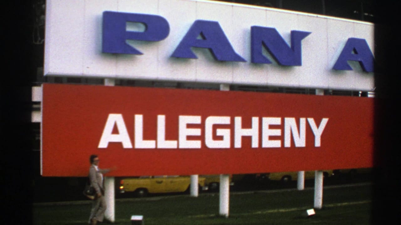 Woman walking past large Pan Am and Allegheny airline sign with yellow taxis behind.