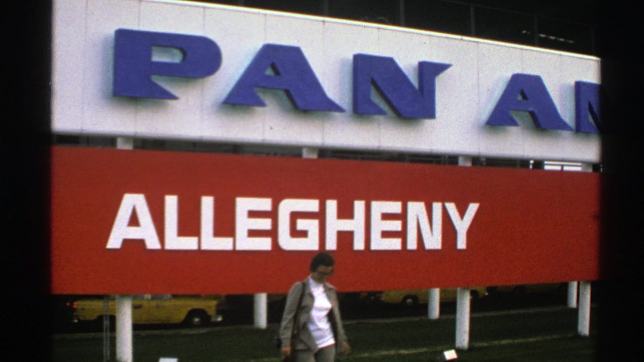 1976 Norway 8mm frame showing a woman near large Pan Am and Allegheny airport signage with yellow taxis in the background.