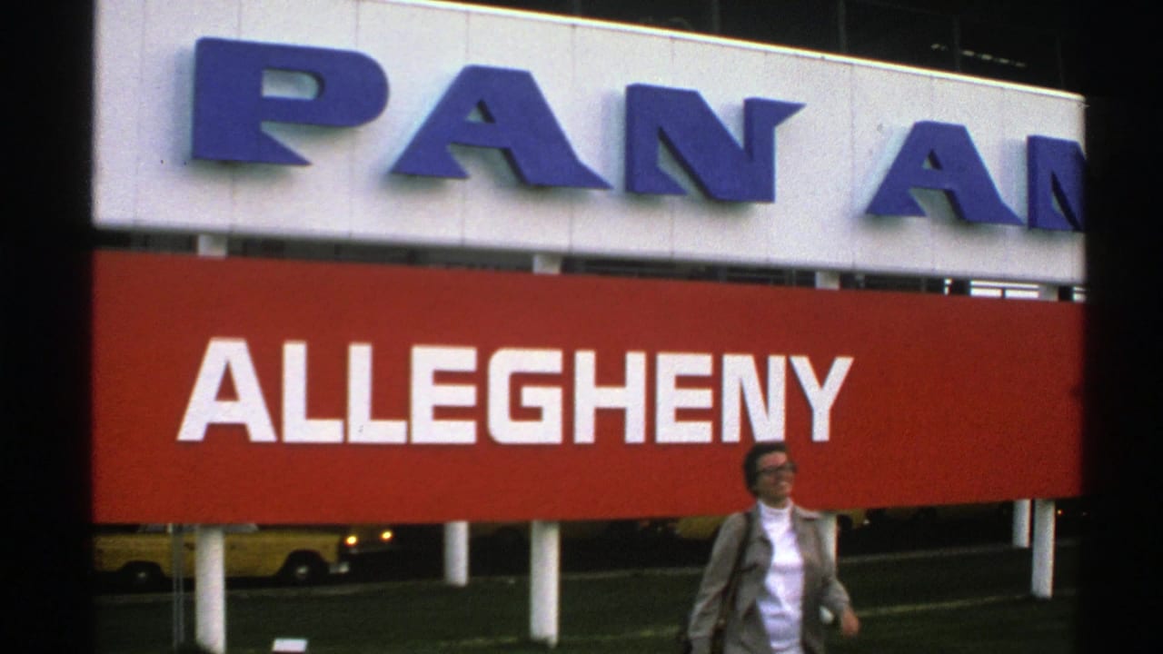 1976 Norway 8mm frame with a woman walking in front of bold Allegheny signage and partial Pan Am lettering above.