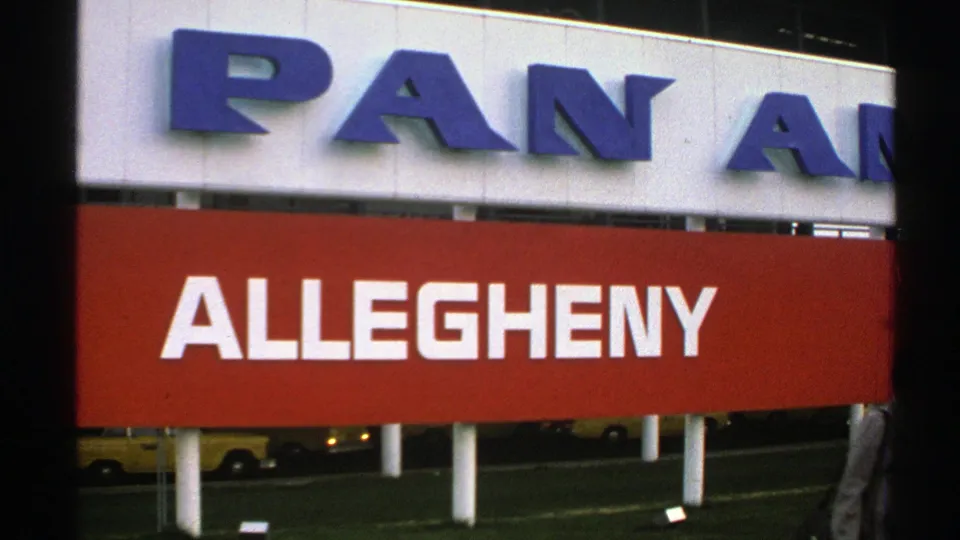 1976 Norway 8mm frame centered on the red Allegheny sign beneath partial Pan Am lettering, with the passerby nearly out of frame.