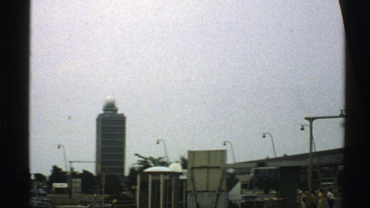 Tall building seen beyond road lights and terminal-area structures.