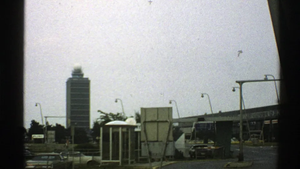 A 1976 Norway street view shows a tall tower and nearby road infrastructure from a moving home-movie camera.