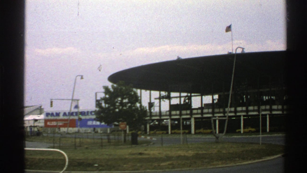 1976 Norway 8mm view of a modernist airport terminal with a circular roof, Pan Am sign, flagpole, roadway, and dark window-frame borders.