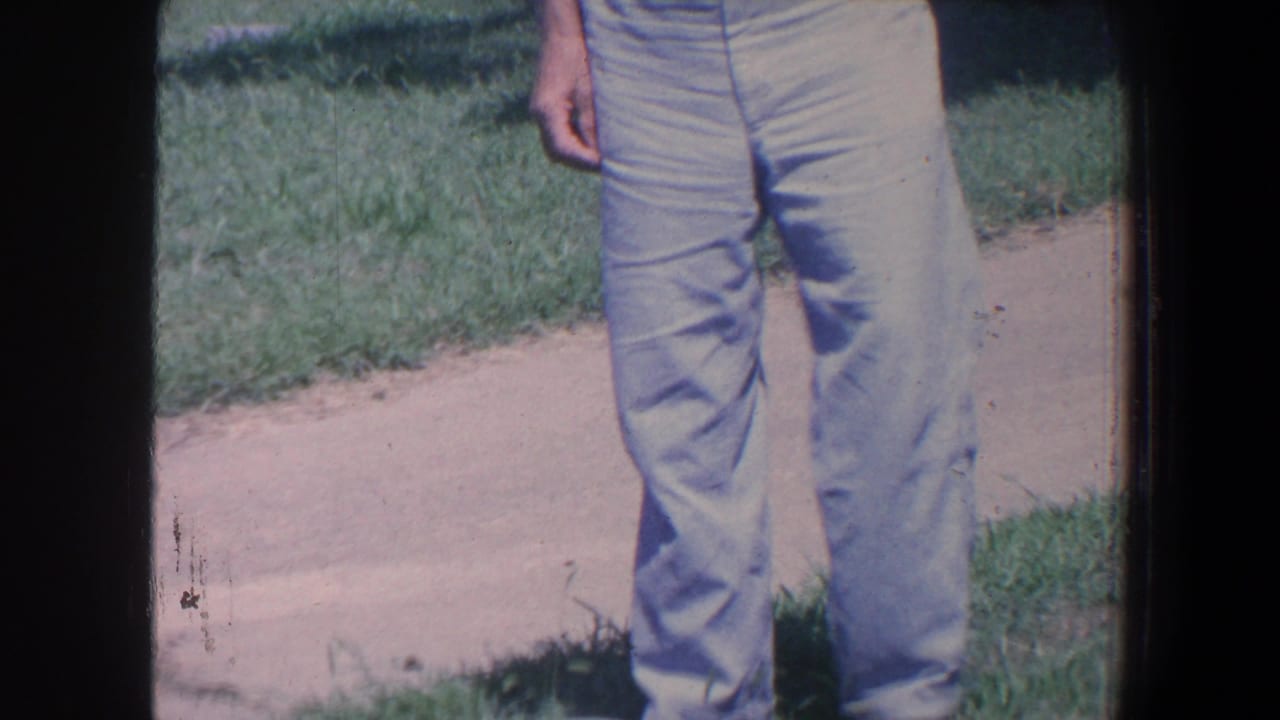 Cropped view of a man standing on grass near a pale cemetery path.