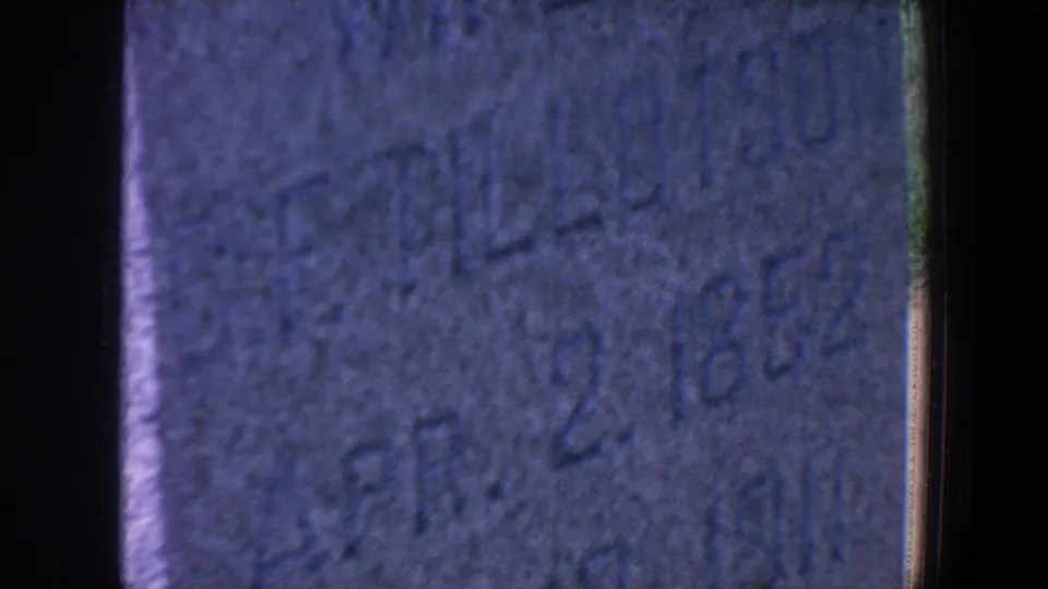 Blue-tinted 8mm frame of a gravestone inscription with partial wording and the date Apr. 2, 1852.