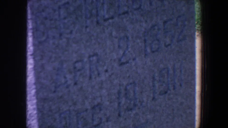 1959 Iowa 8mm close-up of a weathered gravestone with partial Elizabeth inscription and 1911 date.