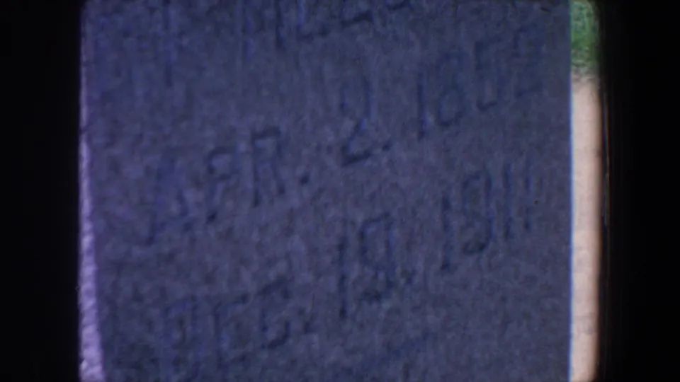 1959 Iowa 8mm frame with a close, soft view of a tombstone face and heavy dark gate edges.