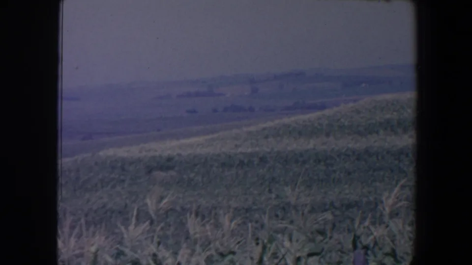 The frame settles on a grassy Iowa hillside and distant agricultural fields, with no person clearly centered in view.