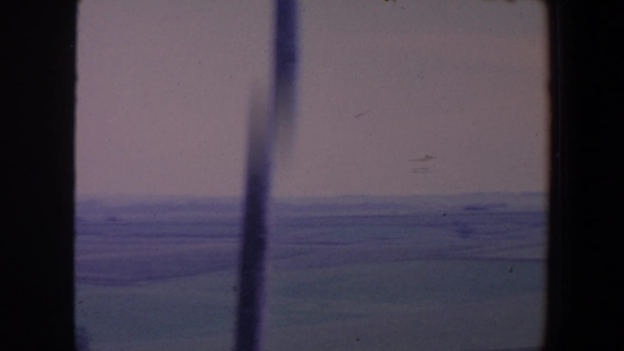 Soft rural horizon with fields, haze, and vertical window framing.