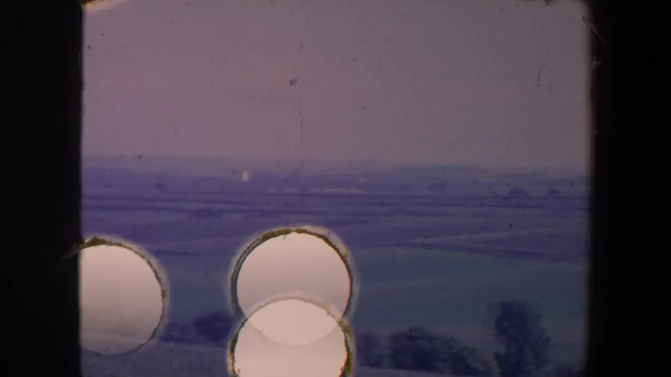 End-frame damage overlays a 1959 Iowa countryside view, with circular bright marks across fields and trees.