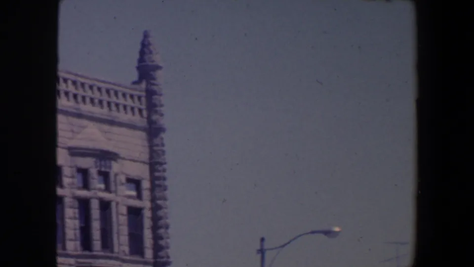 1959 Iowa 8mm frame showing the upper corner of an ornate stone public-looking building with a pointed spire and streetlamp.
