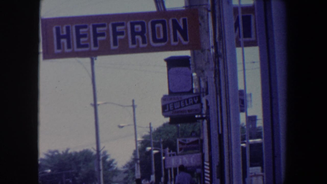 Street view with Heffron sign, jewelry sign, storefronts, trees, and streetlights.