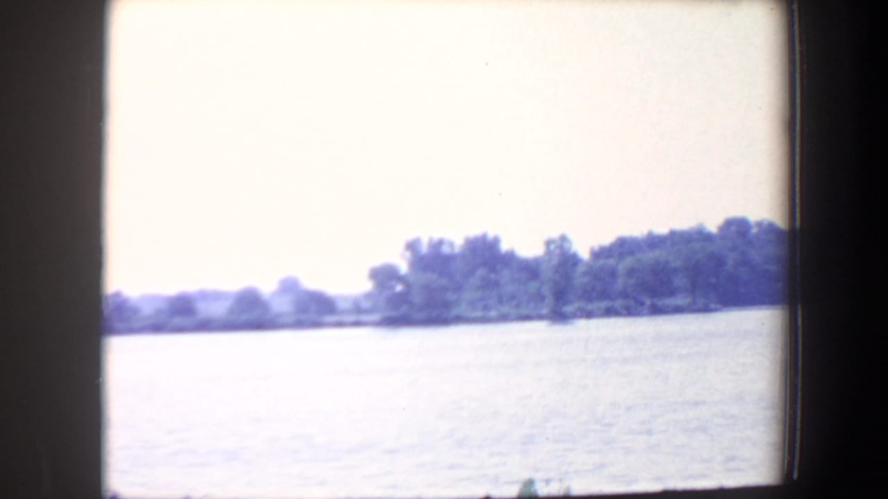 Wide water view with distant tree-lined shore under a pale sky.