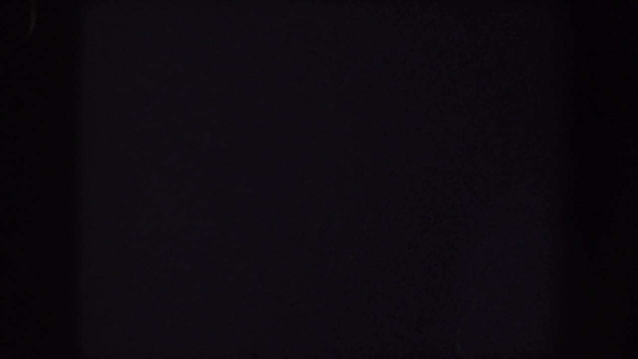 Underexposed 1959 Iowa 8mm frame with soft vertical darkness and faint reddish-purple color noise.
