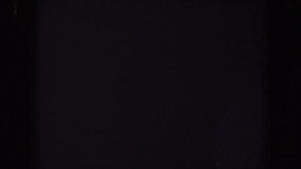Underexposed 1959 Iowa 8mm frame with soft vertical darkness and faint reddish-purple color noise.