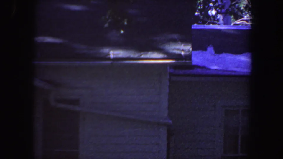 1959 Iowa 8mm frame catches a lower, cropped view of the house exterior, including guttering, siding, partial windows, and snow on the roof.