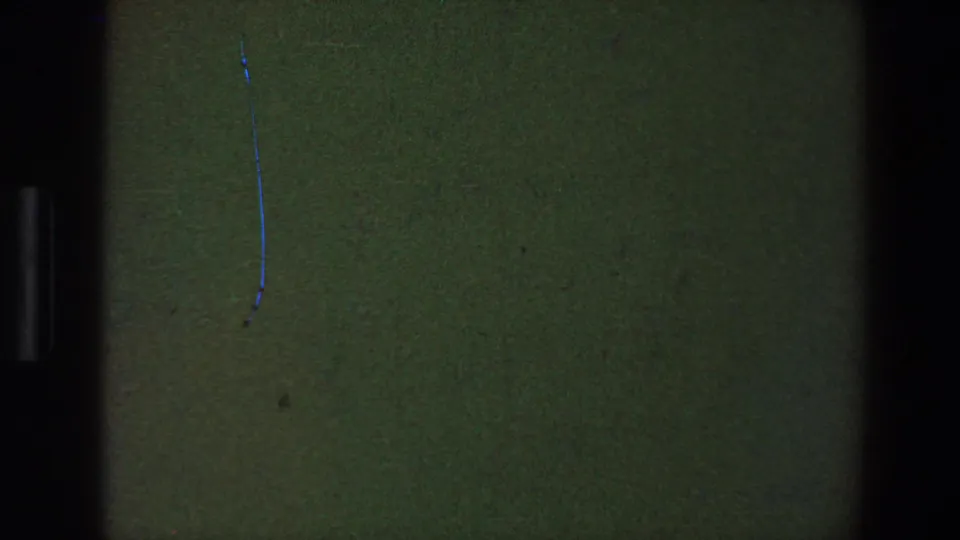 1973 Saint Paul 8mm frame with a blank green-black field, central gate shadow, dust, and a thin blue scratch near the top.