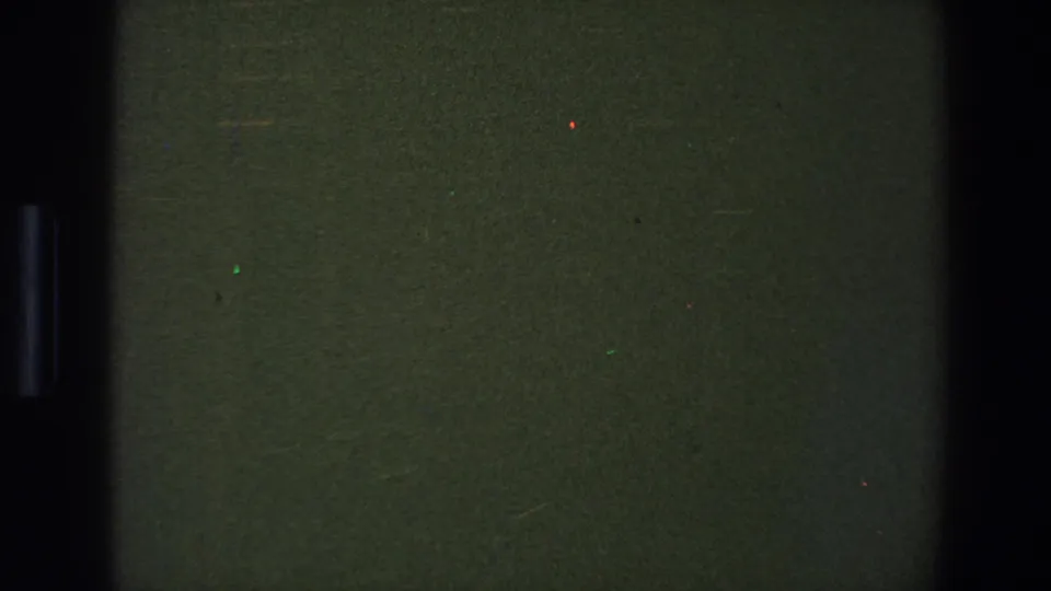 1973 Saint Paul 8mm frame showing a dark green blank field divided by a black vertical film edge with small colored specks.