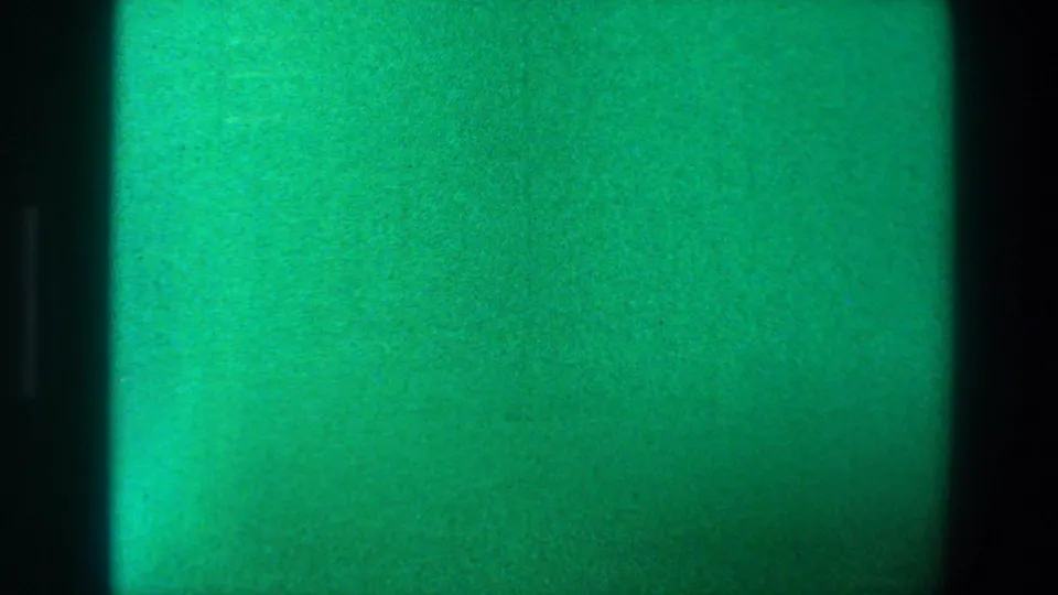 1973 Saint Paul 8mm end-of-reel frame with a bright turquoise-green exposure flare, dark side edges, grain, and uneven color.