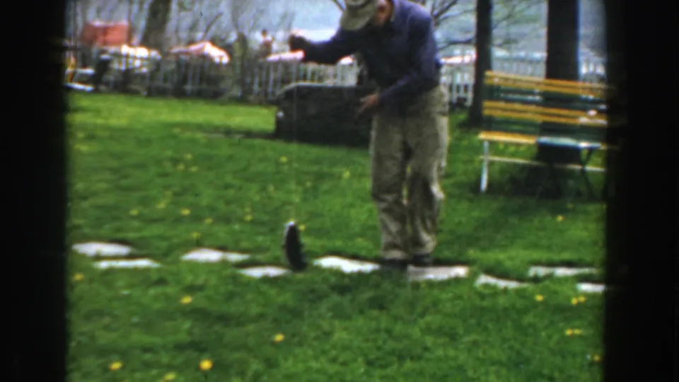 A 1961 Novi, Michigan frame catches the man raising one arm with the fishing line as the small fish flips upright on the grassy lawn.