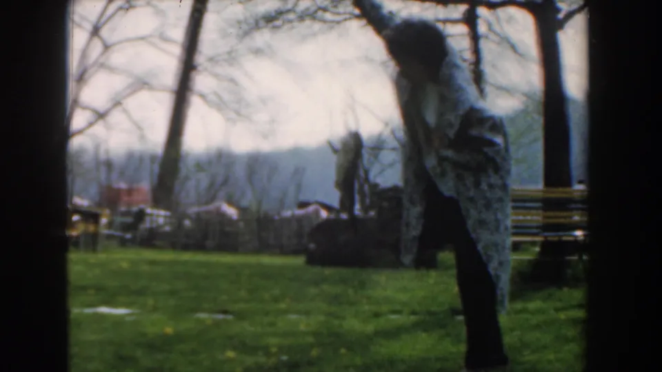 The 1961 Novi footage shows a woman standing on a grassy area near fishing gear, benches, and bare trees.