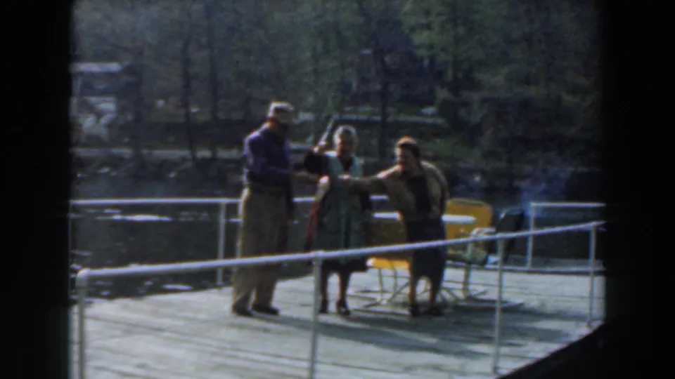 In Novi, Michigan in 1961, three adults stand on a dock by calm water as a fish is displayed toward the camera.