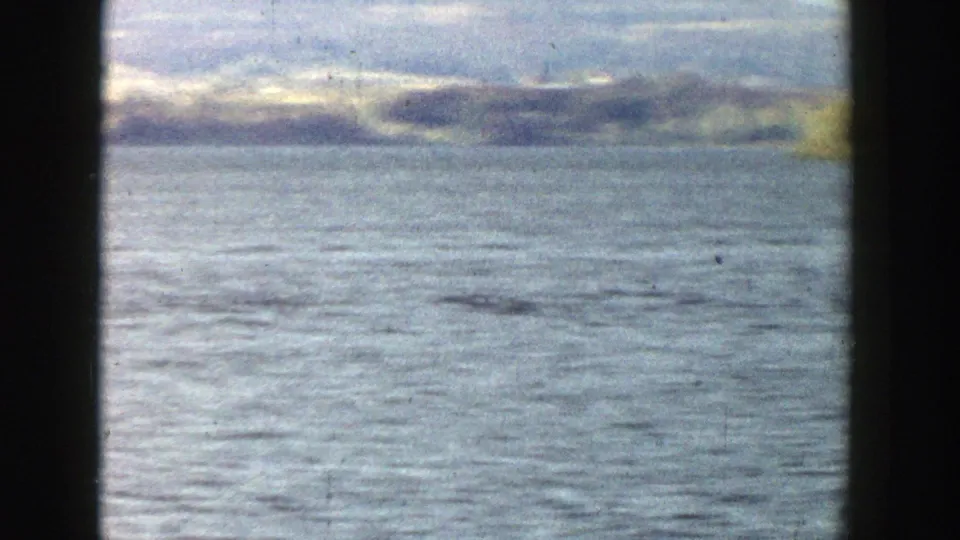 1957 Wisconsin 8mm view of open lake water and distant autumn shoreline, partly framed by dark window-like edges.