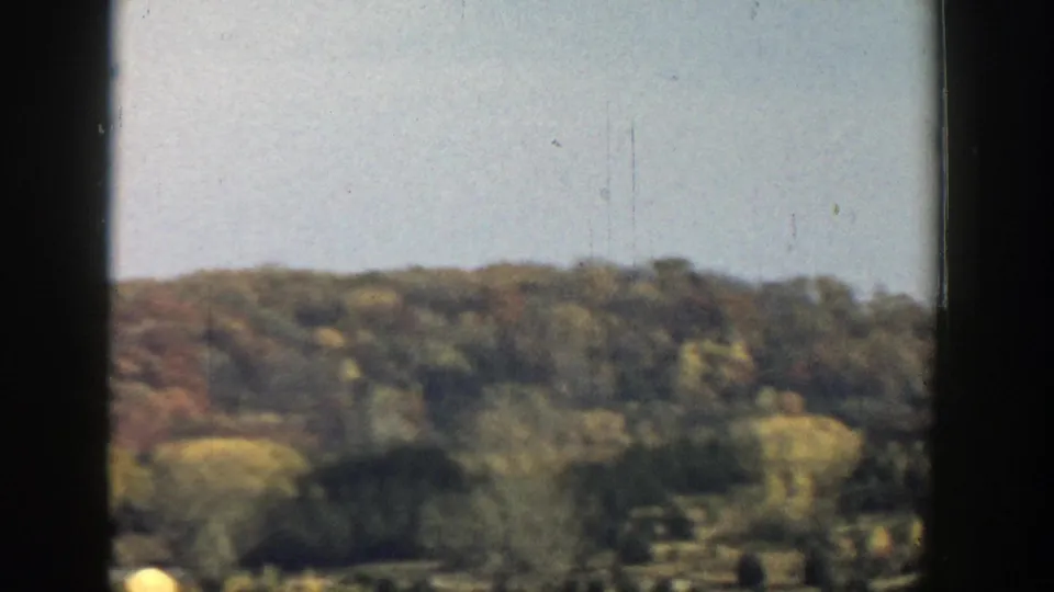 Rolling wooded Wisconsin hills in muted 8mm color, with the view divided by dark interior framing.