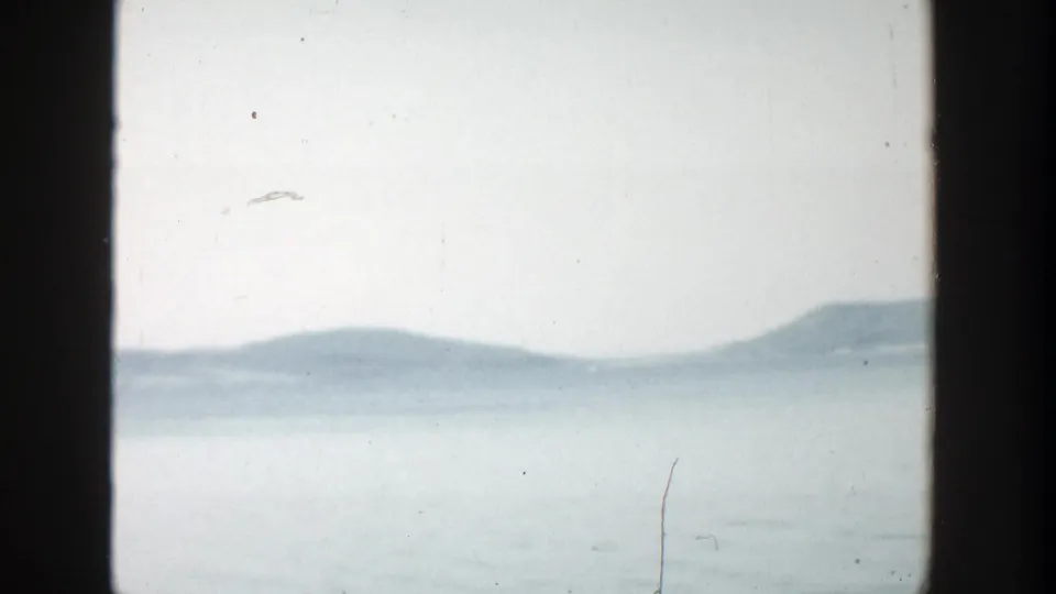 1957 Wisconsin 8mm still showing a muted lake or bay view with low hills along the far shore.