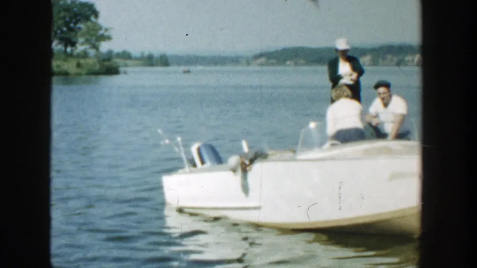 1957 Wisconsin lake scene with a white motorboat close to the camera and family members arranged near the stern.