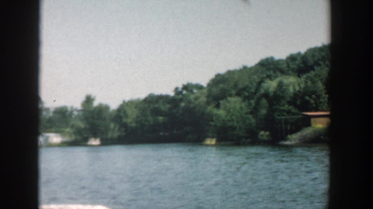 Lake water and wooded shoreline seen through dark vertical framing.