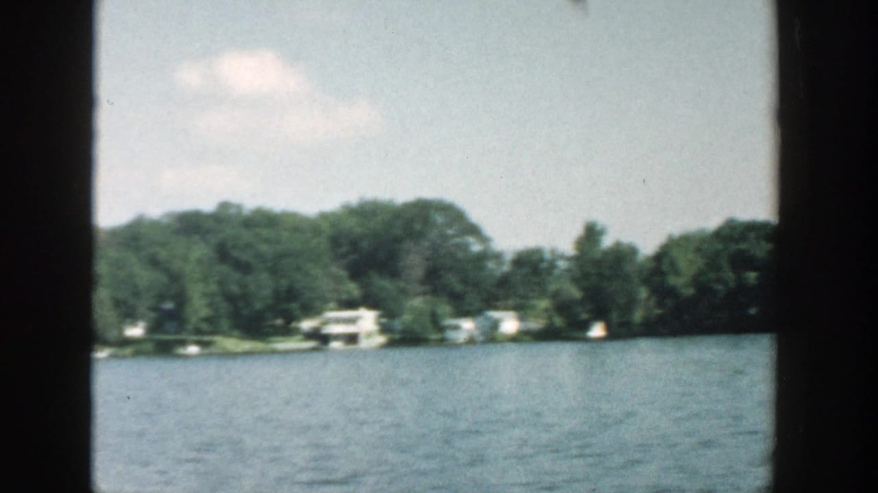 Distant lakeshore with trees, cottages, and calm water.
