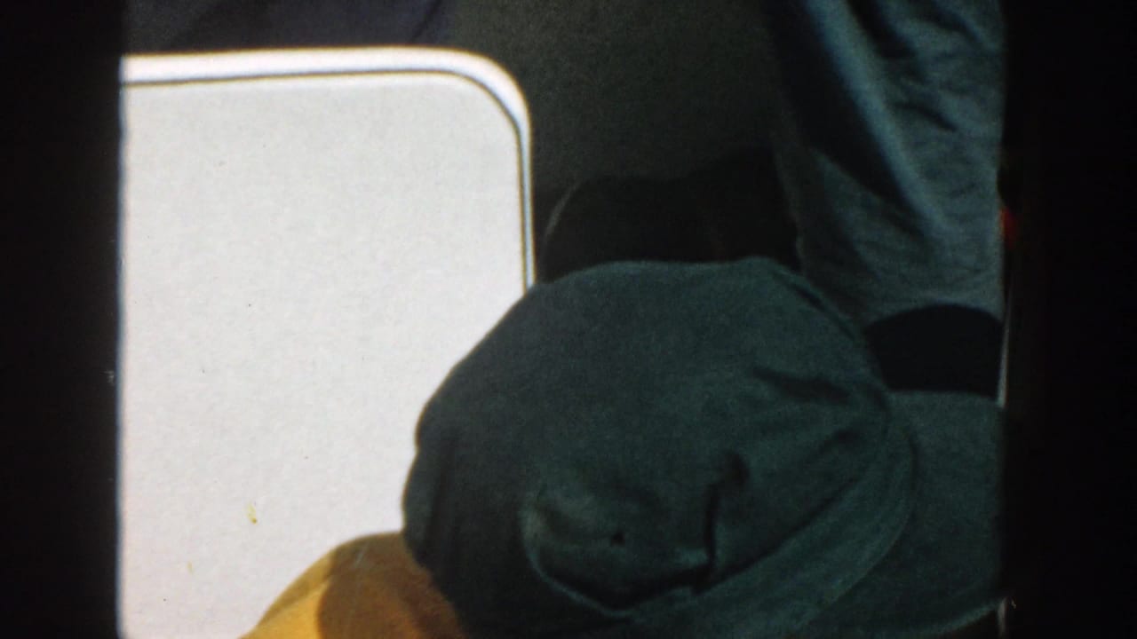 Close view of a man in a green cap near white boat seating.