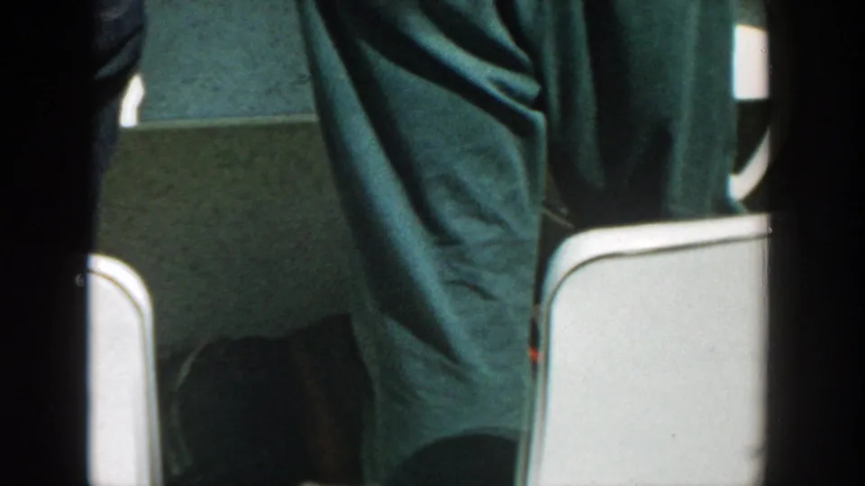 Tight 8mm frame of a standing adult's dark trousers beside white boat seating in the Wisconsin boating footage.